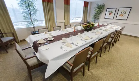 Dining table with chairs, place settings, flowers and framed fruit pictures