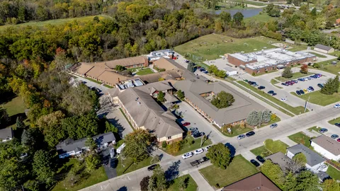 Aerial view of buildings, parking spaces and surrounding trees
