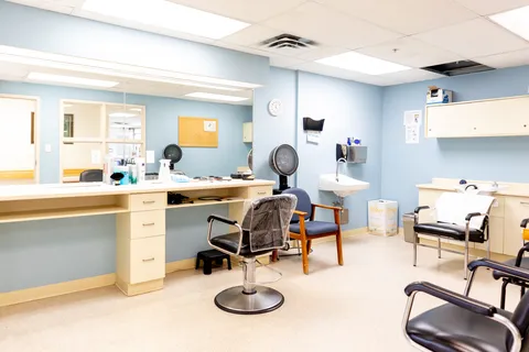 Salon with a styling chair, mirrors, hair dryers and a sink
