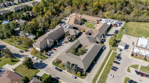 Aerial view of connected buildings with a courtyard and parking spaces