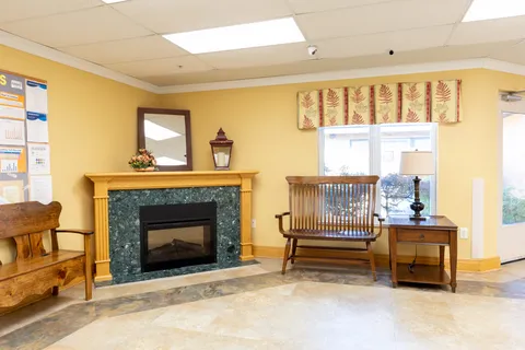 Wooden benches beside a fireplace, mirror and window