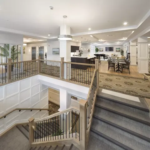 Staircase with dark railings opening onto a seating area