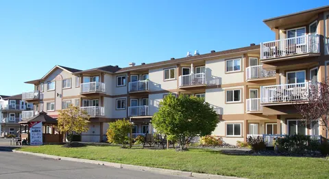 Residence facade with balconies and a lawn along the front.