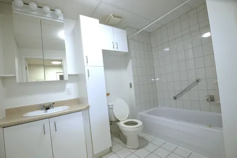 Bathroom with a vanity, toilet, bathtub and grab bar.