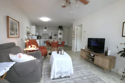 Furnished apartment living area with sofa, television and dining table.