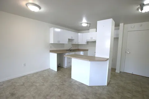 Empty apartment kitchen with white cabinets and a peninsula counter.