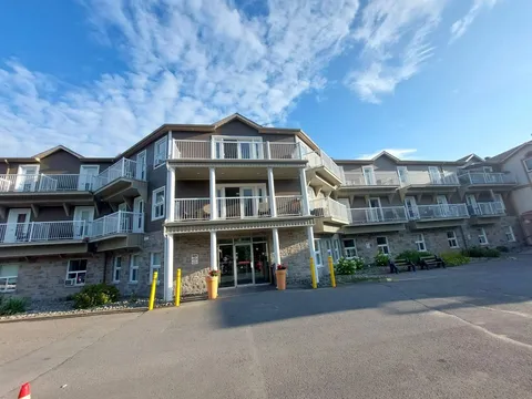 Main entrance beneath balconies with a paved approach.