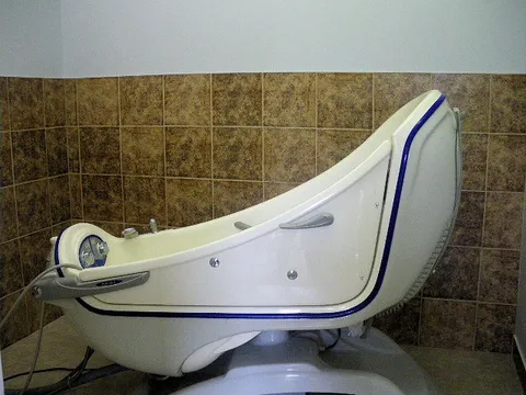 White reclining bathing tub with a side opening against tiled walls