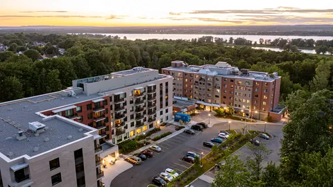 Aerial view of residence buildings, parking and nearby woodland.