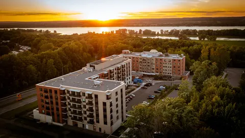 Aerial view of residence buildings beside trees and parking at sunset.