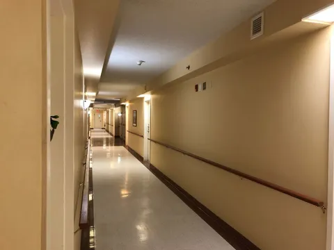 Long corridor with cream walls, handrails and doors
