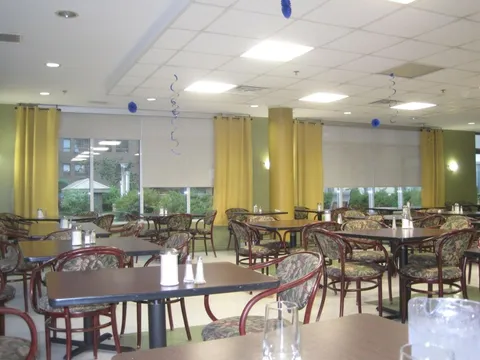 Dining room with square tables, patterned chairs and yellow curtains