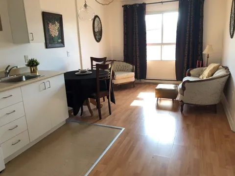 Kitchenette beside a dining table, upholstered chairs and a window