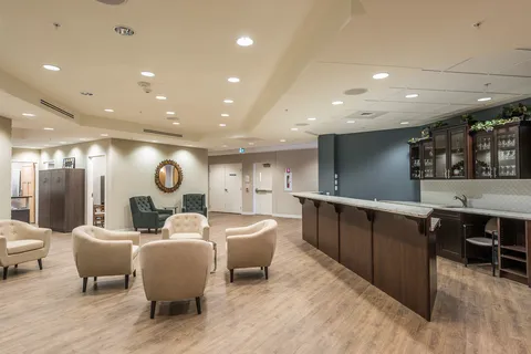 Room with cream armchairs, green chairs, a wooden bar counter and glass cabinets