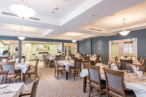Dining room with set tables, wooden chairs and an open doorway toward a fireplace