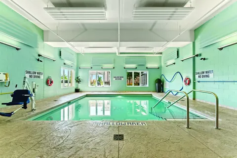 Indoor pool with handrails, tiled walls and large windows