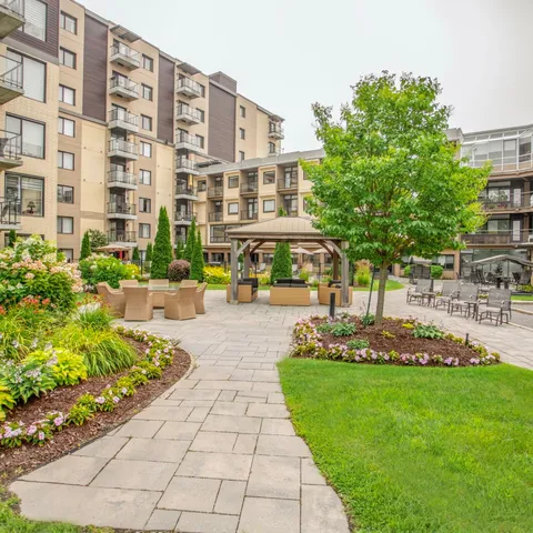 Courtyard with flower beds, a gazebo and seating beside the residence.