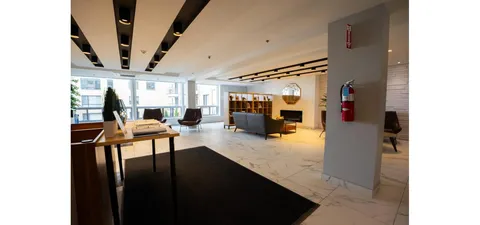 Lobby with a reception desk, fireplace, sofa and armchairs.