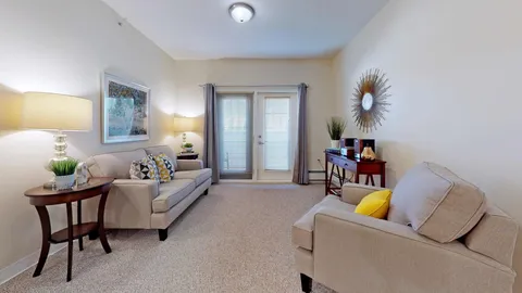 Sitting area with a sofa, armchair and doors opening to a balcony