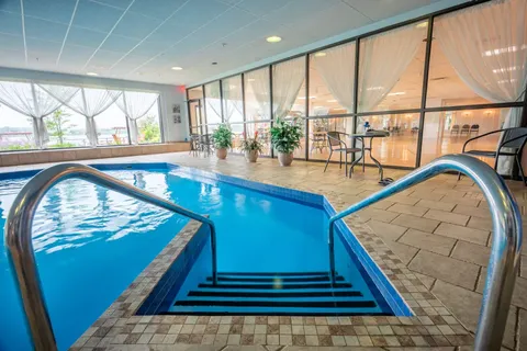 Indoor swimming pool with handrails and large windows.