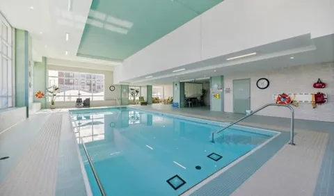 Indoor swimming pool with steps, handrails and large windows