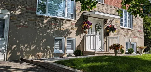 Stone residence facade with a covered entrance and hanging flower baskets.