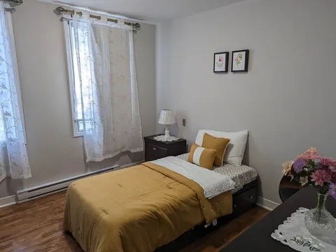 Bedroom with a single bed and sheer window curtains.