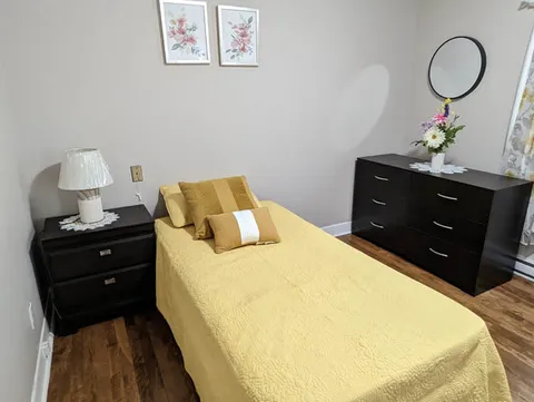 Bedroom with a yellow bedspread and dark wooden dresser.