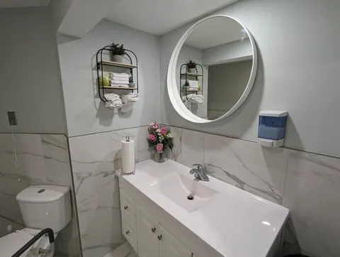 Bathroom with a sink, toilet and round mirror.