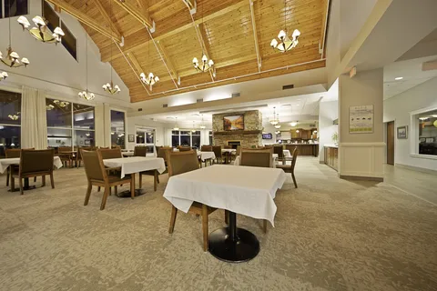 Dining room with set tables beneath a high timber-framed ceiling.
