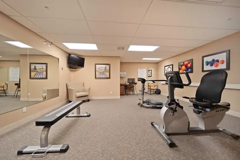 Fitness room with exercise machines and a weight bench.