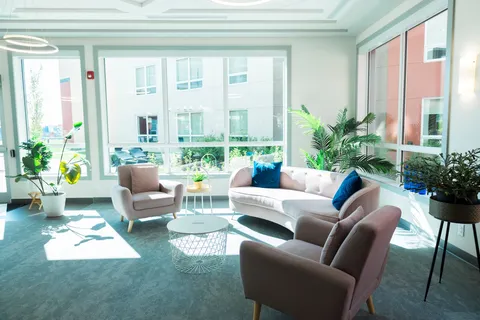 Sunroom with upholstered seating and potted plants.