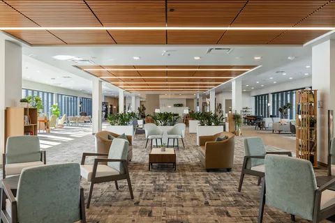 Spacious lounge with upholstered seating beneath a timber ceiling.