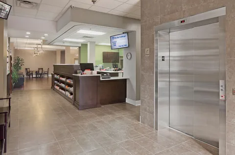 Counter beside an elevator with tables and chairs in the background
