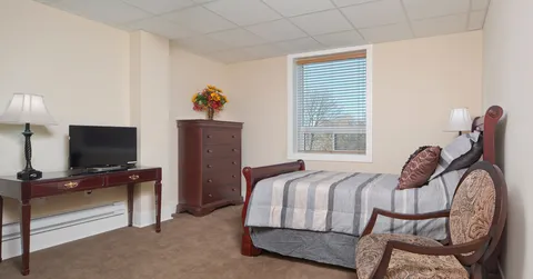 Bedroom with a wooden bed, chest of drawers, chair and television