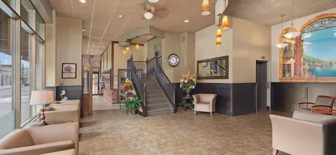 Lobby with armchairs, a staircase, an elevator and large windows