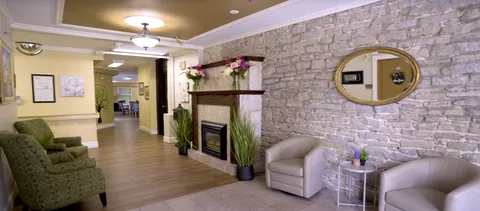 Sitting area with armchairs, a fireplace, stone wall, oval mirror and potted plants