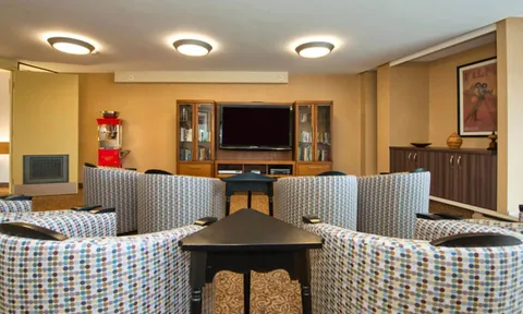 Screening room with upholstered seating and a television.