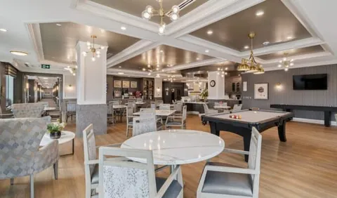Room with a pool table, shuffleboard table and upholstered chairs