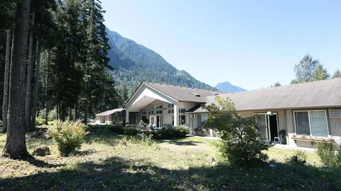 Low residence building with trees, planted grounds and mountains behind