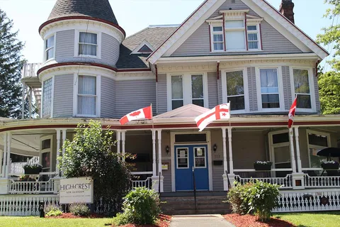 Grey residence with a turret, covered porch and Canadian flags