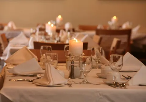 Dining tables set with glasses, folded napkins and candles