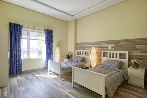 Bedroom with two beds, white furniture and large windows