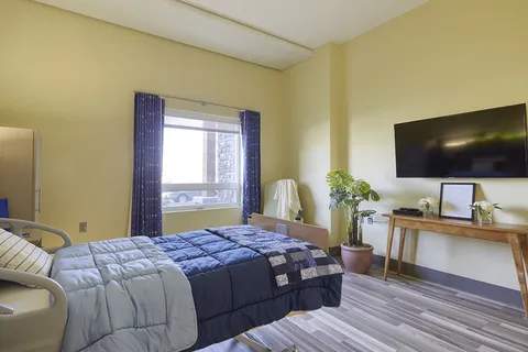Bedroom with a blue bedspread, television and a wooden console table