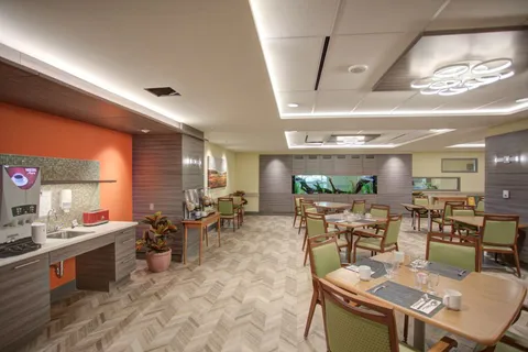 Tables and green chairs beside a kitchenette and serving counter