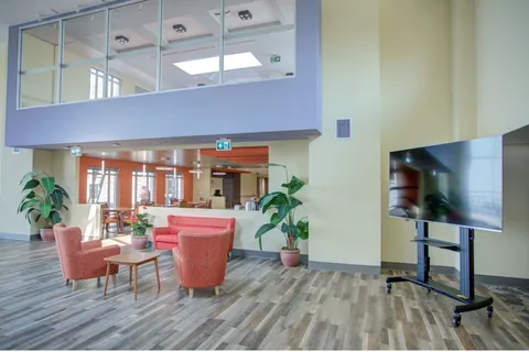 Atrium seating area with red armchairs and large windows
