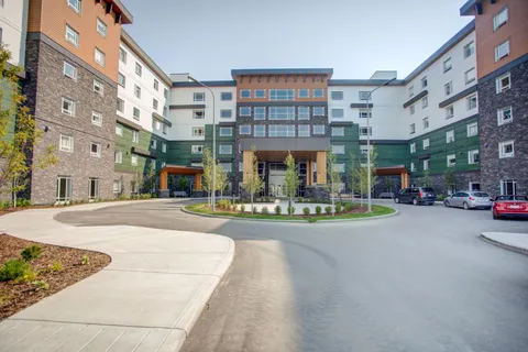 Residential building around a paved courtyard with trees and flower beds
