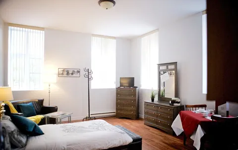 Studio with bed, dresser and dining area.