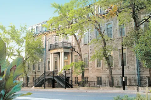 Historic stone residence exterior along a tree-lined street.