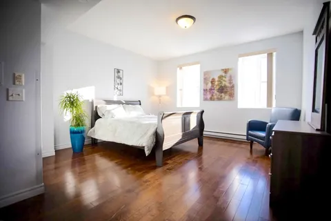 Bedroom with a wooden bed frame and armchair.